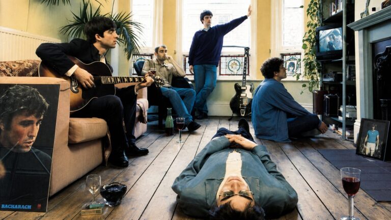 Capa do álbum Definitely Maybe do Oasis com os integrantes reunidos na sala da casa de Bonehead